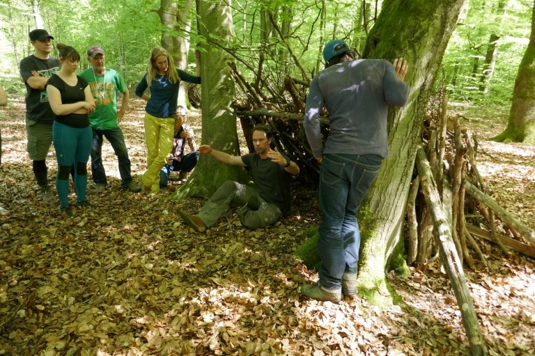 Matthias Schloo (sitzend) in einem Survival Unterstand (Foto: Niedersächsische Landesforsten)