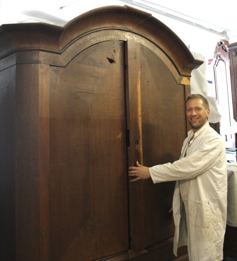 Restaurator Sven Gödeke während seiner Arbeit an dem Schrank aus dem 18. Jahrhundert. Das aufgebrochene Schloss und die Spuren des Granateneinschlags sind gut zu erkennen. © Bachmann-Museum Bremervörde
